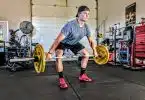 man carrying yellow barbell