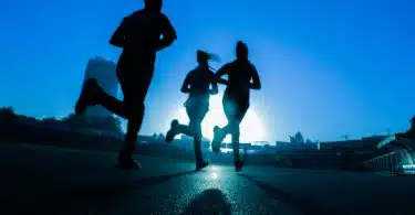 silhouette of three women running on grey concrete road