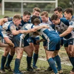 Joueurs de rugby amateurs en cercle avant un match de Fédérale 2 poule 3, maillots bleus et blancs sur terrain herbeux