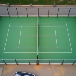 Vue aérienne d'un terrain de padel extérieur avec vitres et gazon synthétique vert