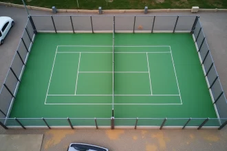 Vue aérienne d'un terrain de padel extérieur avec vitres et gazon synthétique vert